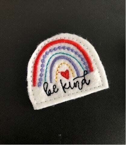 "Be Kind" rainbow feltie hair bow accessory on black background