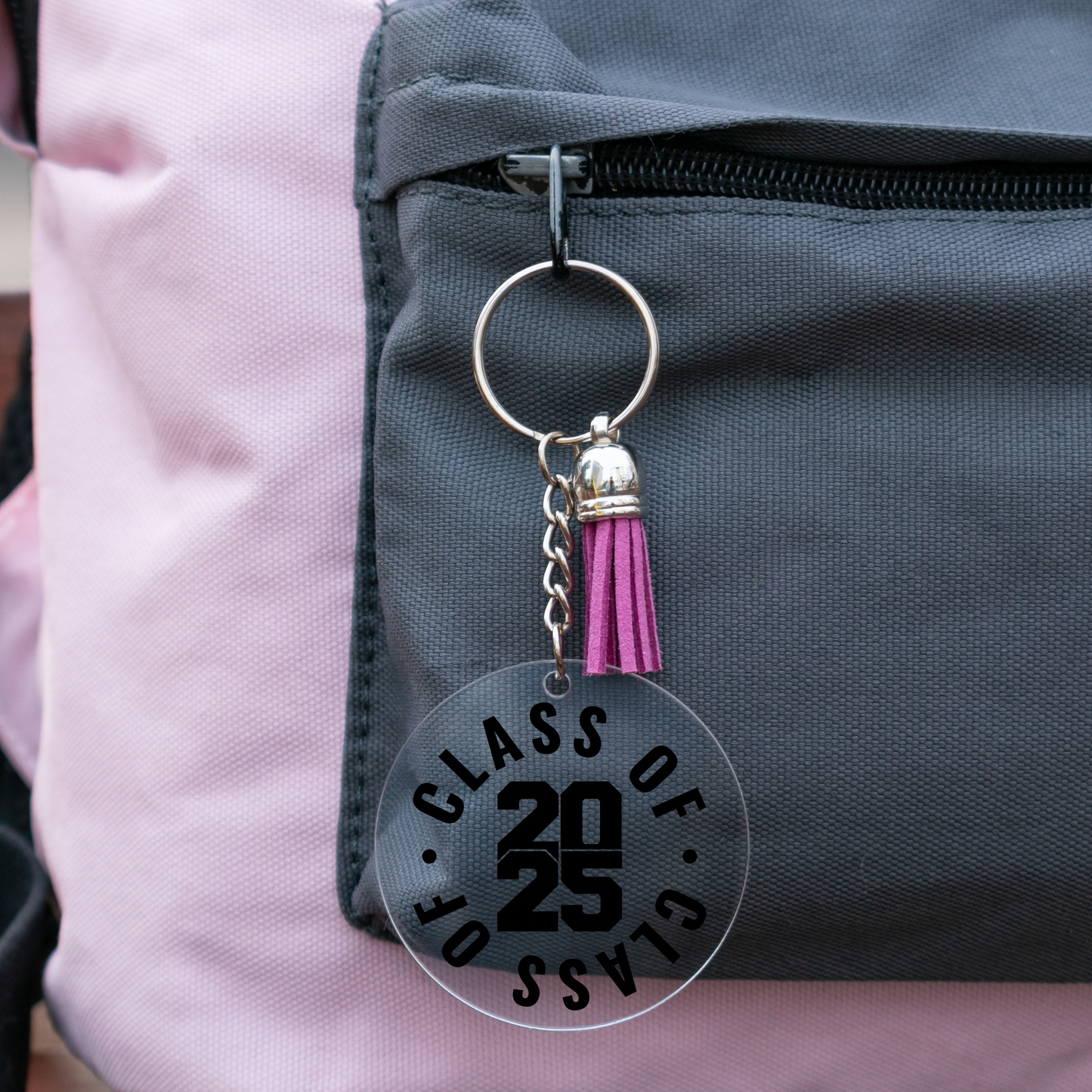 Class of 2025 acrylic graduation keychain with purple tassel attached to a backpack.