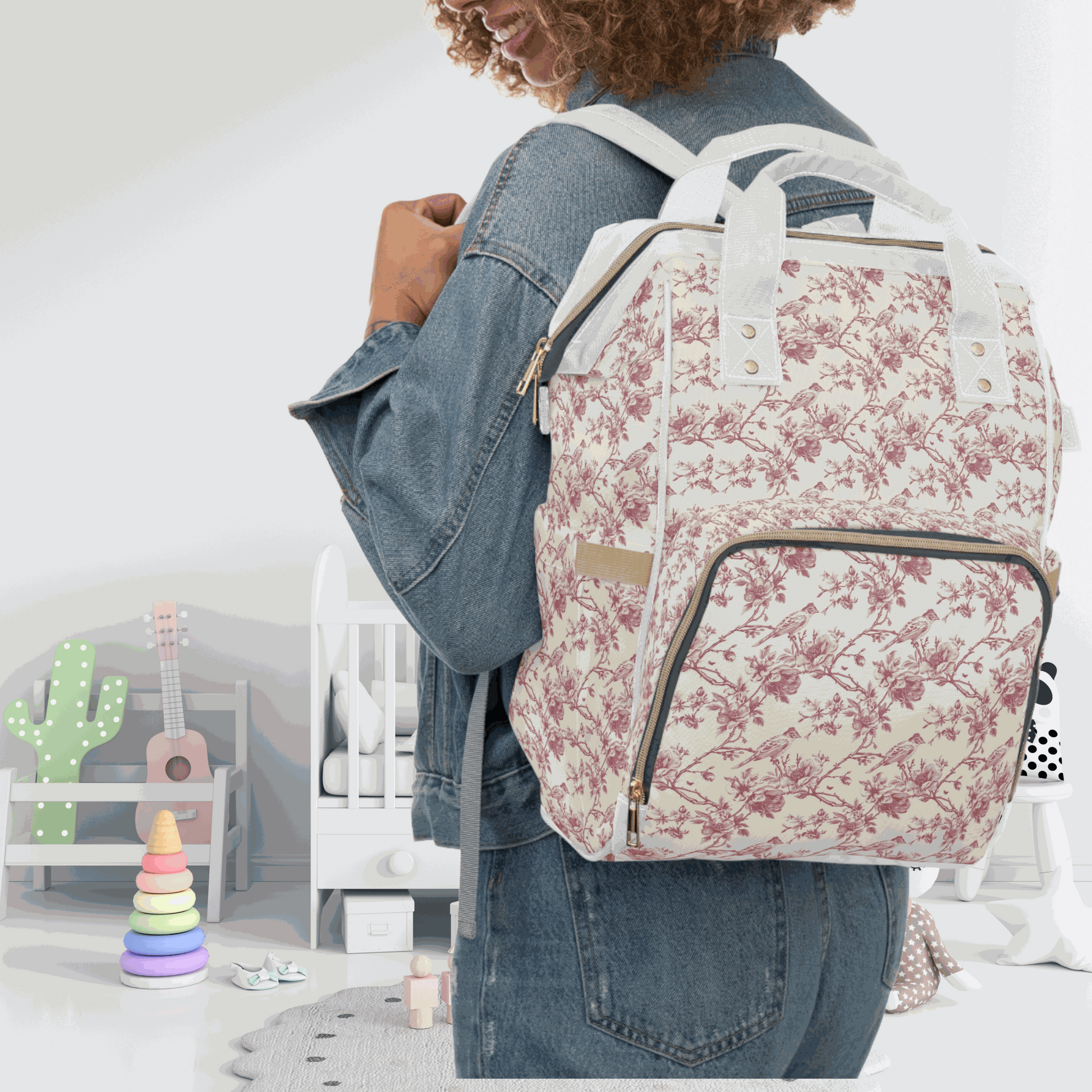 Pink toile diaper backpack worn by a stylish parent in a nursery setting.