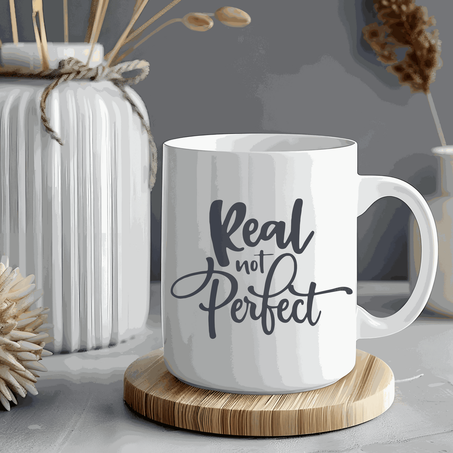 Ceramic coffee mug with "Real Not Perfect" text design.