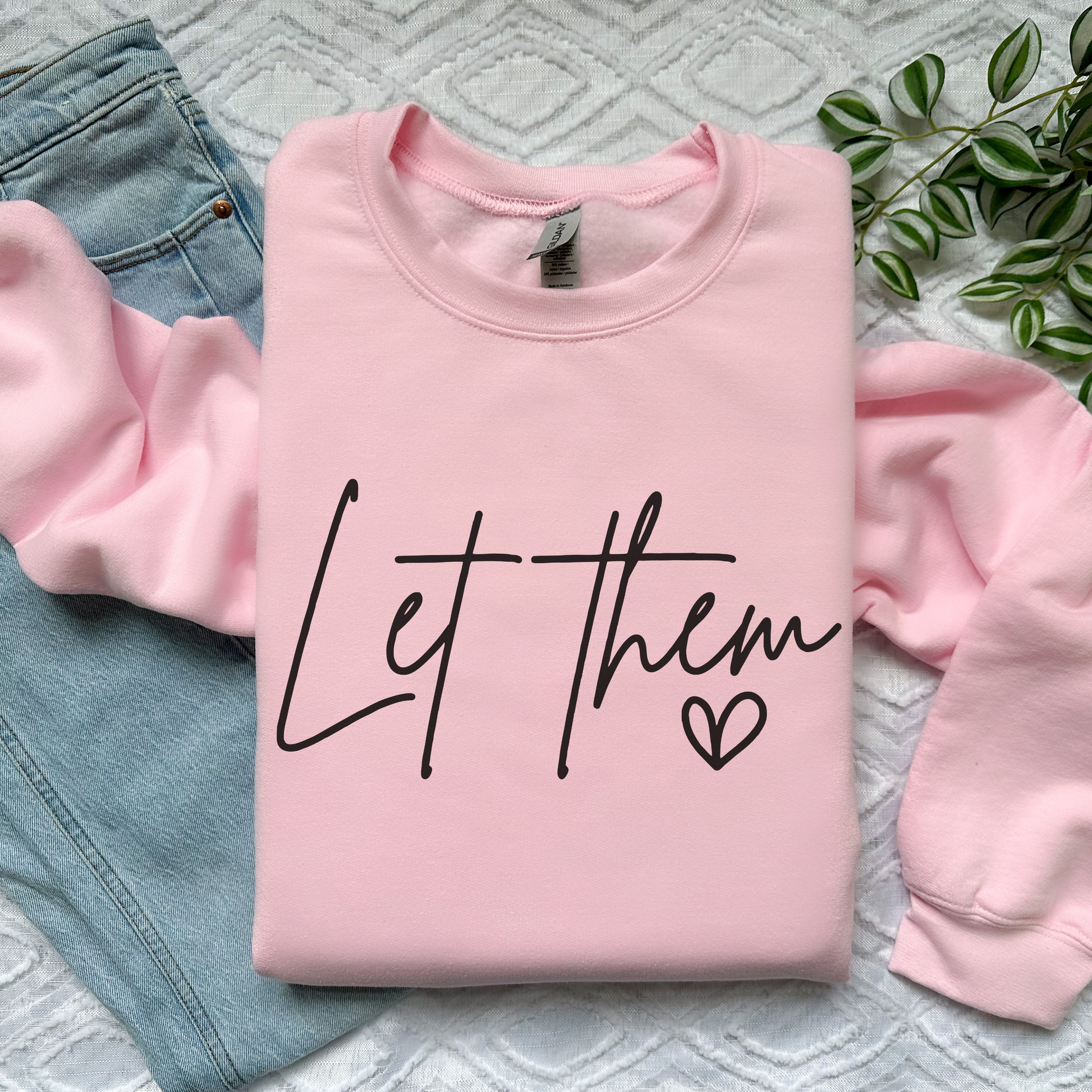 Pink "Let Them" sweatshirt with handwritten script and heart accent on cozy fabric.