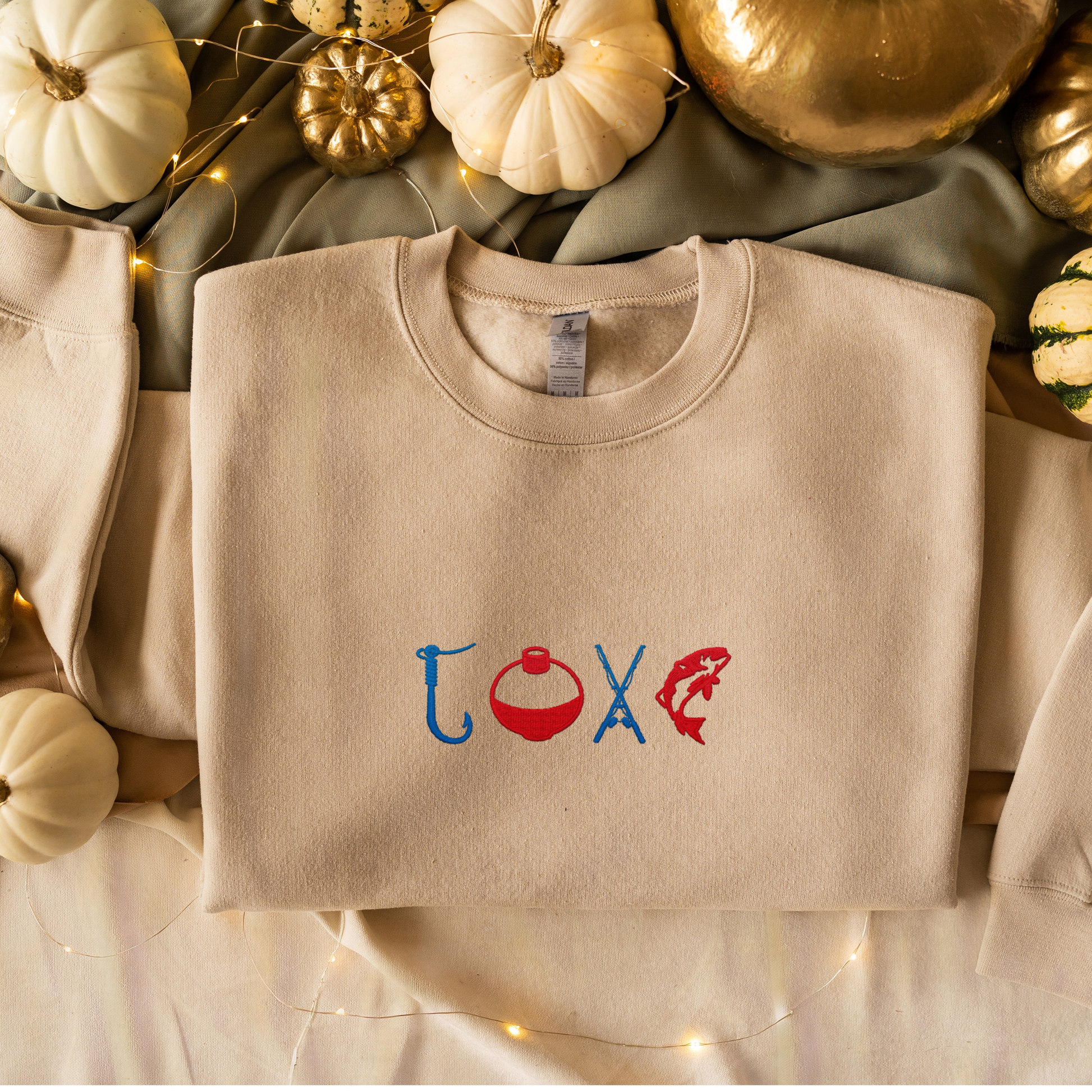 Fishermen Love Fishing Embroidered Crewneck with fishing-themed design on beige fabric, surrounded by decorative pumpkins.