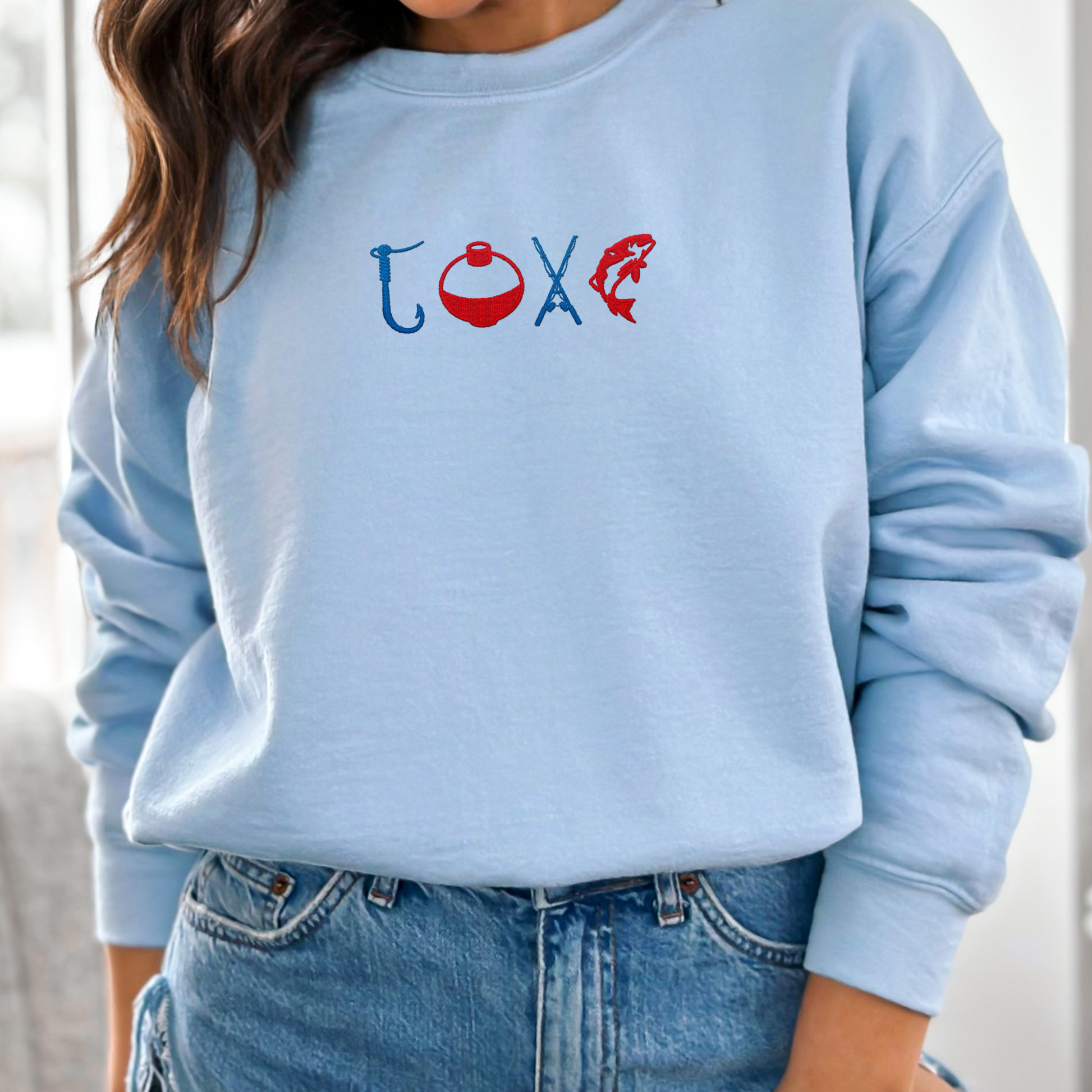 Fishermen Love Fishing Embroidered Crewneck in light blue worn by a person.