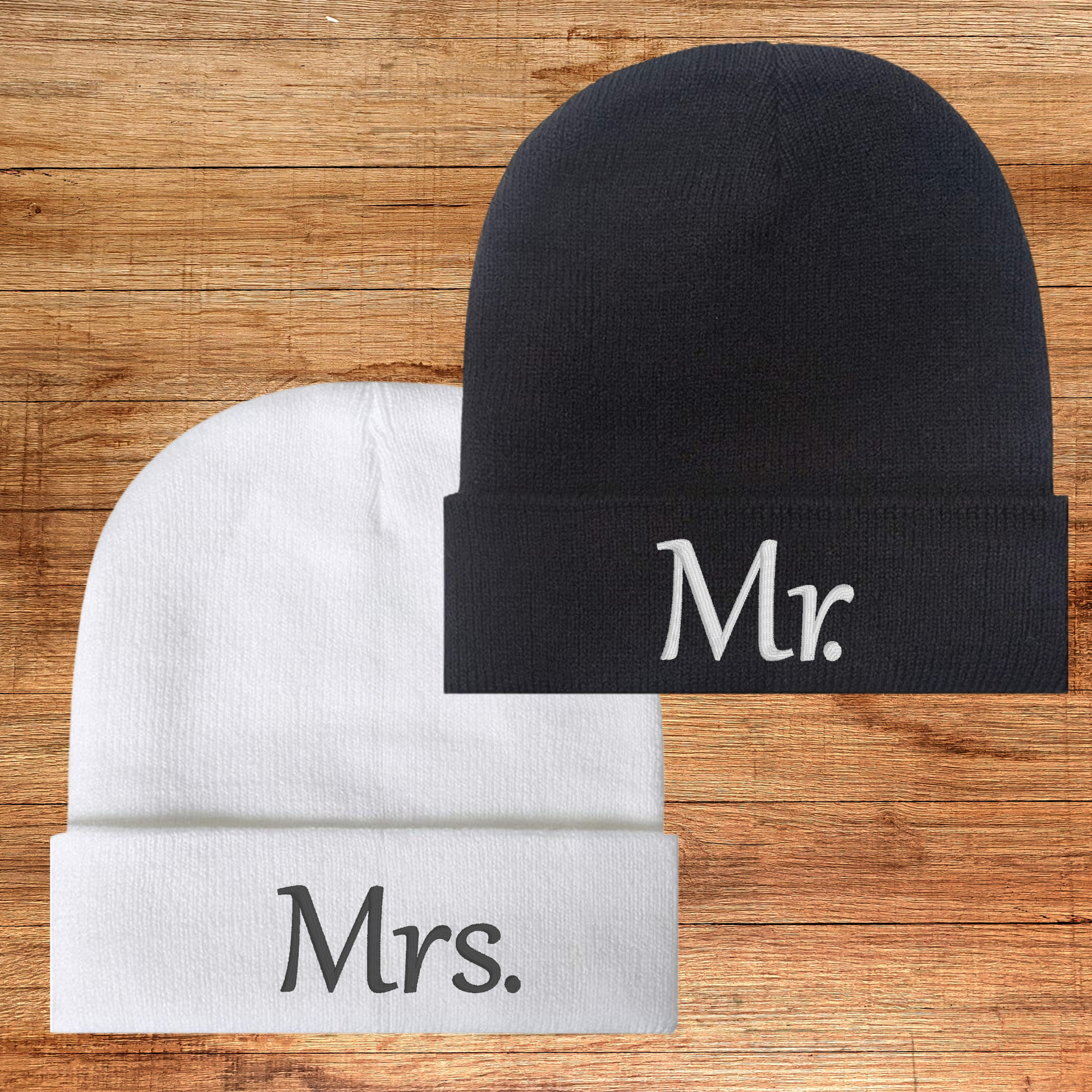 Mr. and Mrs. embroidered beanies in black and white on wooden background.