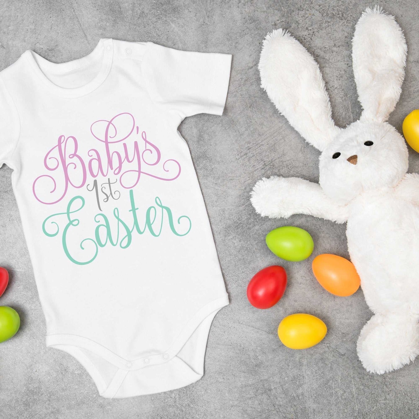 Personalized baby onesie for pregnancy announcement with Easter design, 100% cotton, shown with Easter eggs and plush bunny.