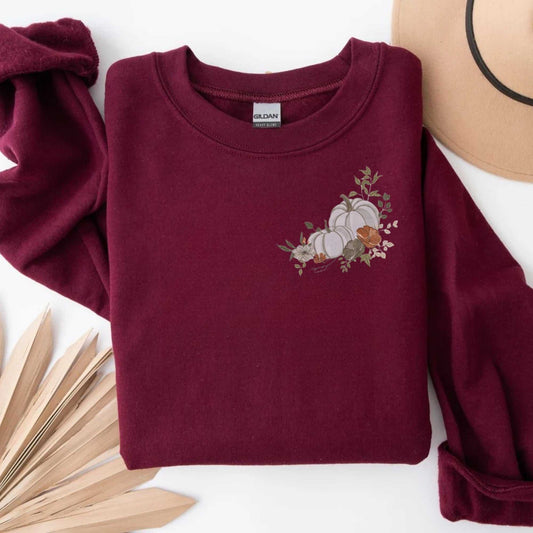 Maroon sweatshirt with white floral pumpkin embroidery, cozy fall sweater, unisex cotton blend perfect for autumn.