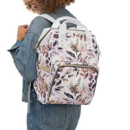 Floral diaper bag backpack with stylish pink design worn by woman in denim jacket, perfect for baby essentials and new moms.