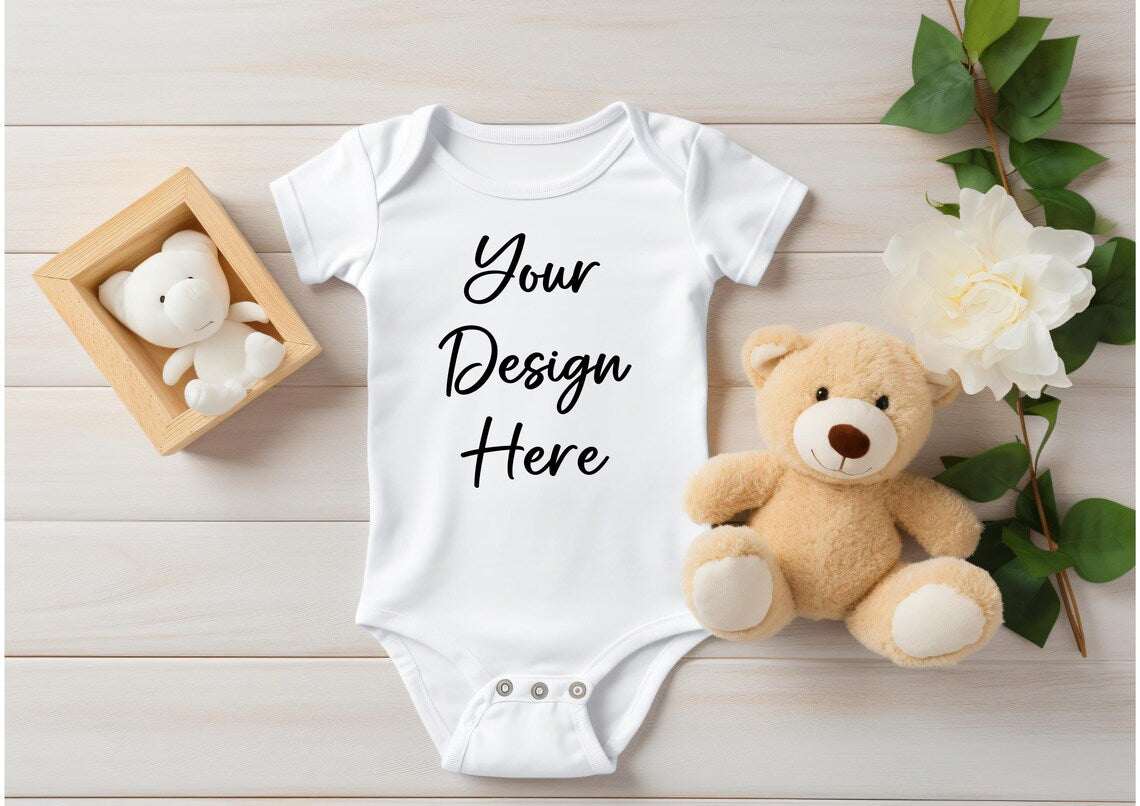 Personaliized baby onesie for personalized pregnancy announcement, displayed with teddy bear and flowers.