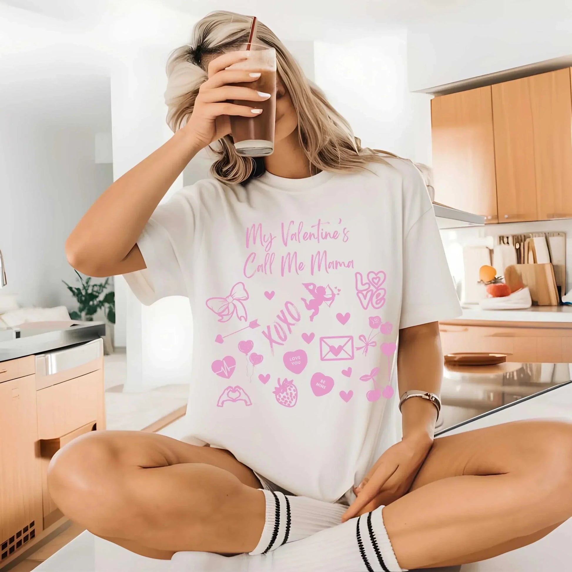 Women's Valentine's Day t-shirt reading "My Valentine's Call Me Mama" in a cozy kitchen setting.