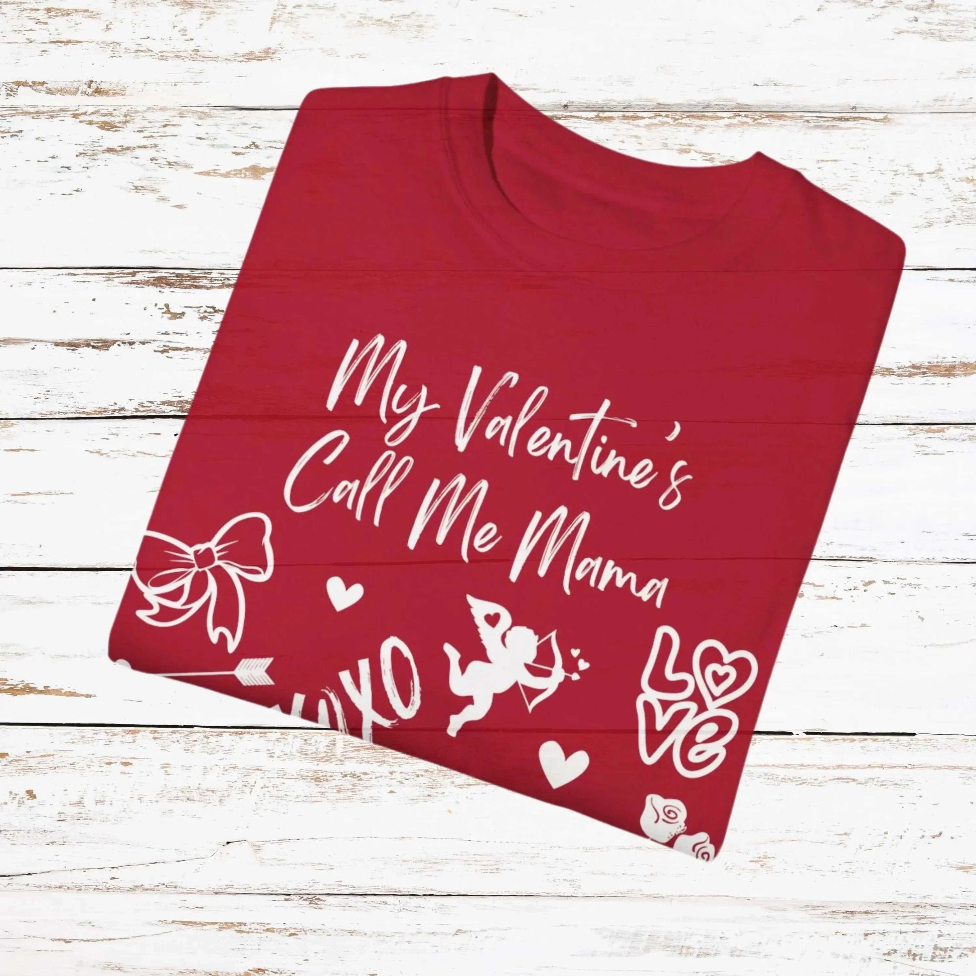 Red "My Valentine's Call Me Mama" T-shirt with white Valentine's doodles on a wooden background.