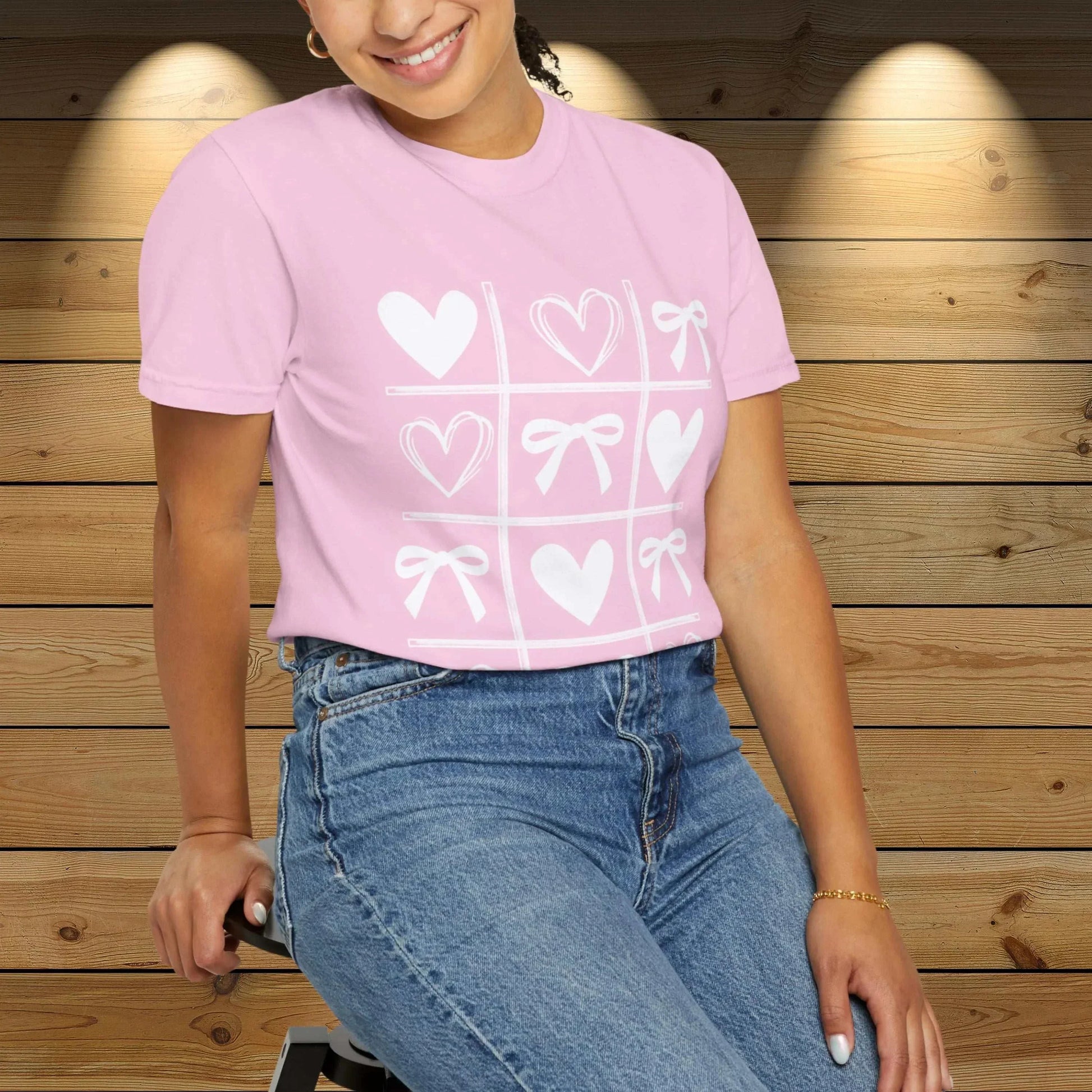 Valentine's Day shirt with heart and bow tic-tac-toe design in pink, worn by a woman.