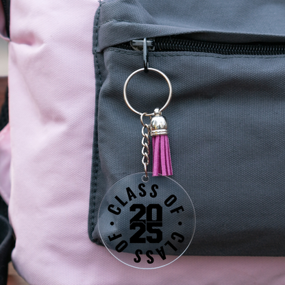 Class of 2025 acrylic graduation keychain with purple tassel attached to a backpack.