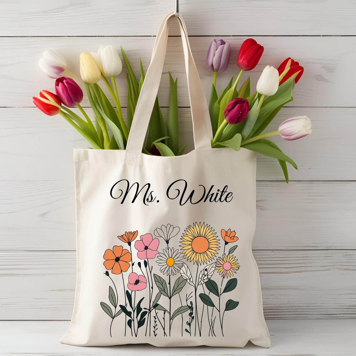 Personalized wildflower tote bag with teacher's name in elegant font and colorful floral design, eco-friendly cotton canvas, ideal gift for teachers.