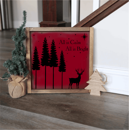 Handmade Christmas wood sign with "All is Calm, All is Bright" text in black on a red background, featuring pine trees and a reindeer silhouette, framed in wood, with hanging hardware.