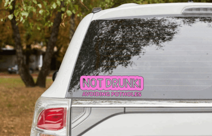 Funny "Not Drunk Avoiding Potholes" car sticker on rear window.