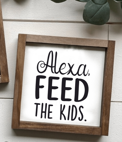 Handcrafted "Alexa, Feed The Kids" framed wood sign with black lettering on white background.
