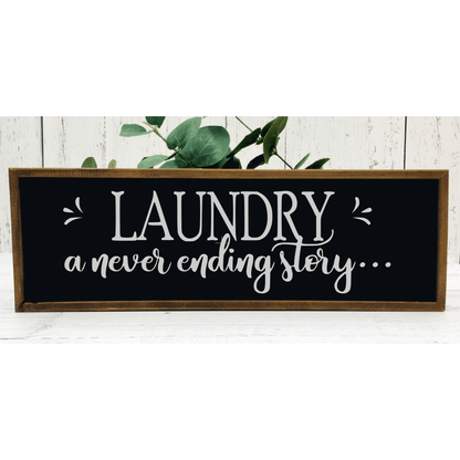 Wood framed sign with "Laundry a never ending story" text in black and white.
