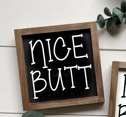 Handcrafted "Nice Butt" wood sign with black background and white lettering, framed in wood.