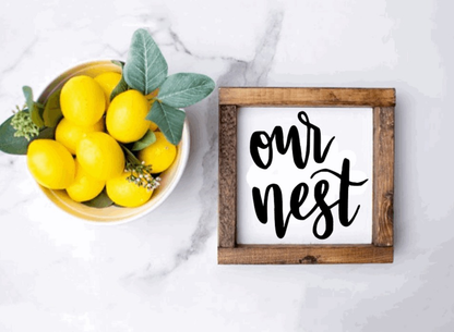 Handcrafted "Our Nest" wood sign with rustic wooden frame and black lettering.