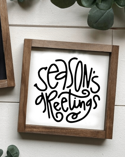 Handcrafted "Season's Greetings" holiday wood sign with black lettering on white background.