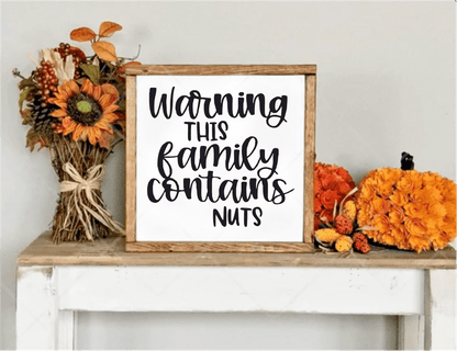 Funny handcrafted wood sign with "Warning This Family Contains Nuts" text, framed in natural wood. Perfect for home decor or as a unique gift.